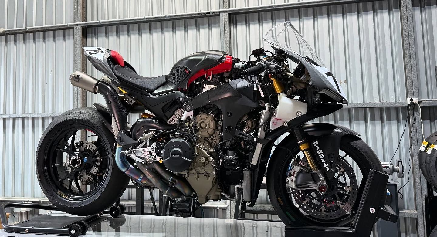 A Ducati V4R trackbike mounted to the workshop bench is receiving a service.