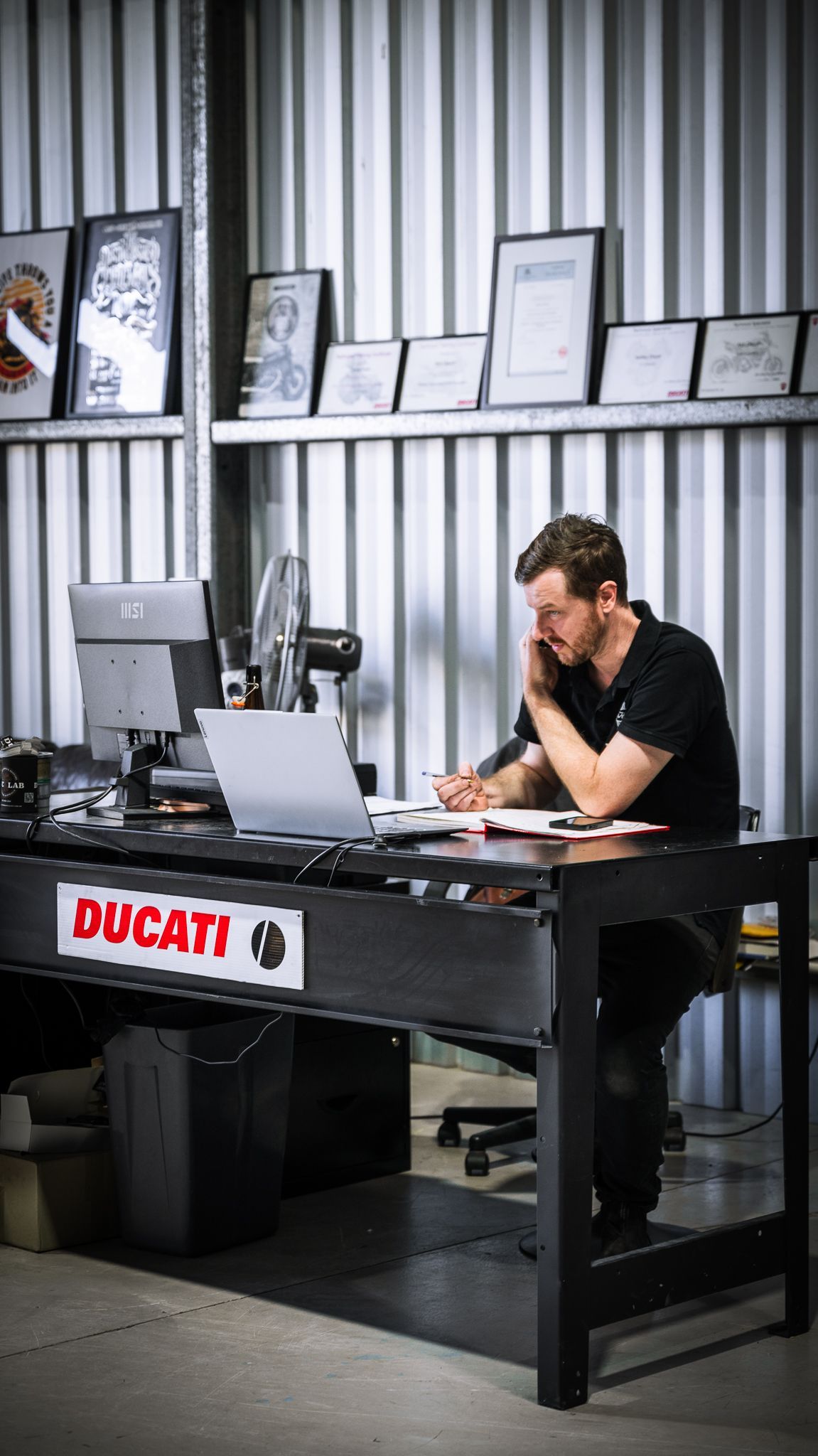 duc lab qualifications and certifications along the wall and owner Ash consulting with a customer on the phone.