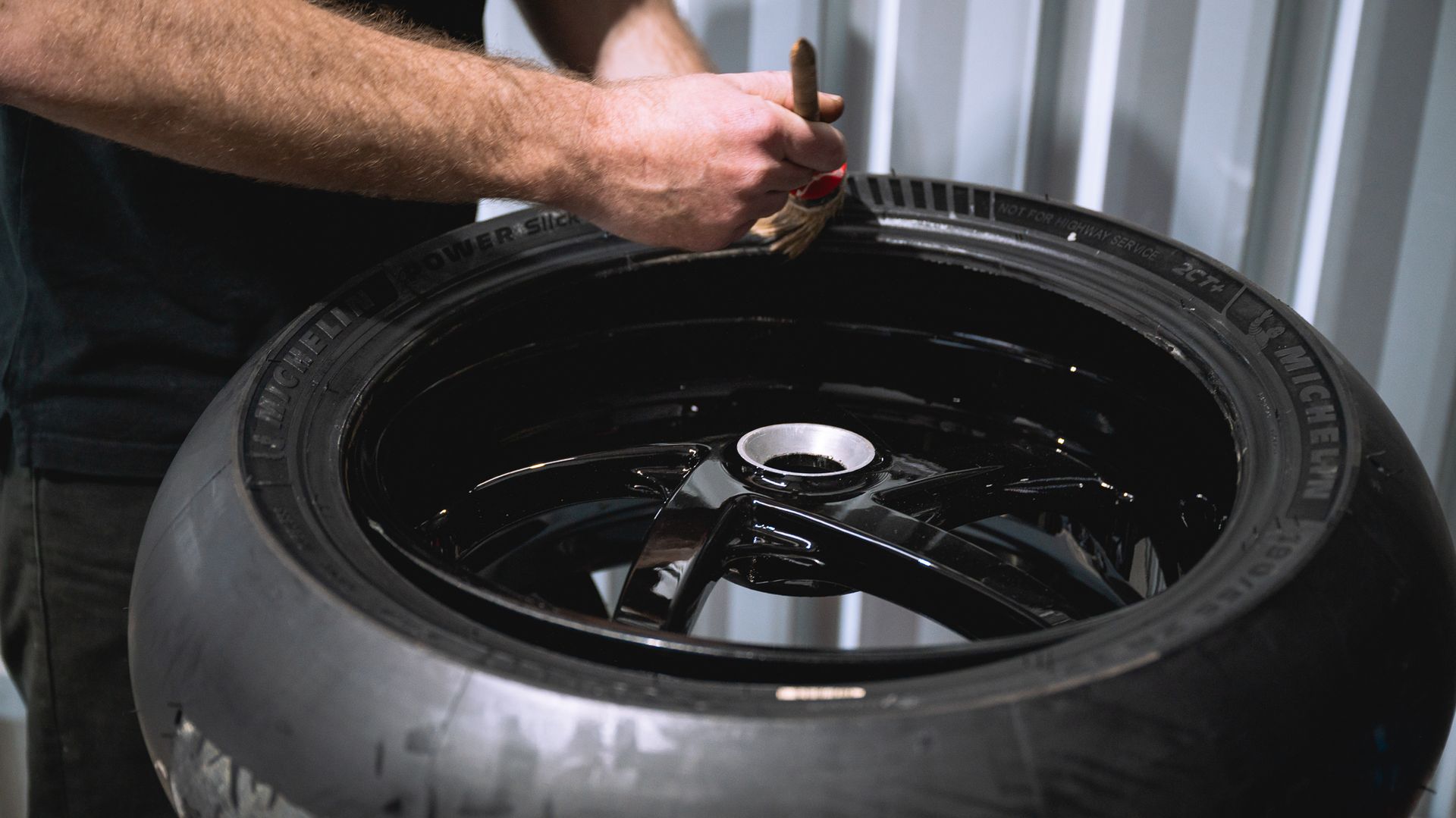 A technician is fitting a brand new Michelin tyre to a motorcycle rim.