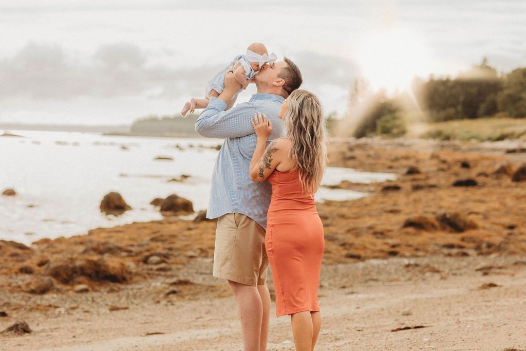Three people on a beach wearing matching coral shirts. Woman in pink shorts, men in khaki shorts.