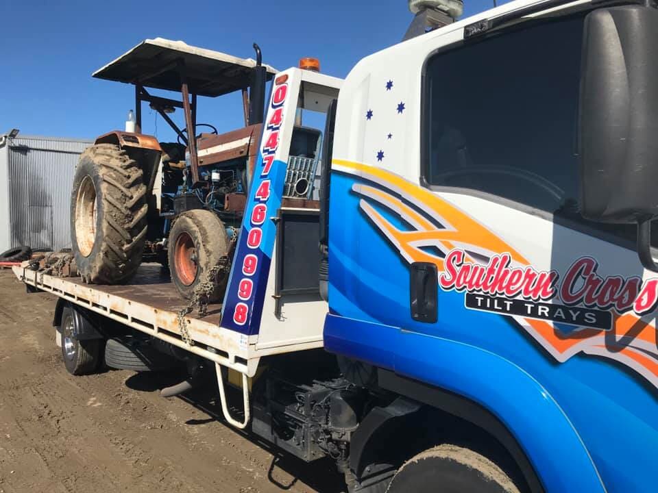 A Tow Truck With a Lift on the Back is Parked in Front of a Building — Southern Cross Tilt Trays in Andergrove, QLD