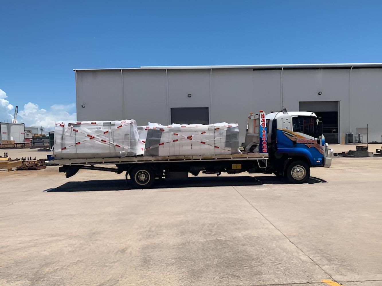 A Blue and White Truck is Parked in Front of a Building — Southern Cross Tilt Trays in Sarina, QLD