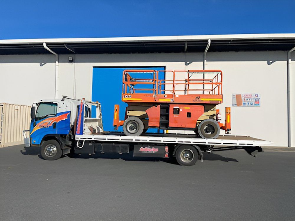 A Tow Truck With a Lift on the Back is Parked in Front of a Building — Southern Cross Tilt Trays in Whitsundays, QLD
