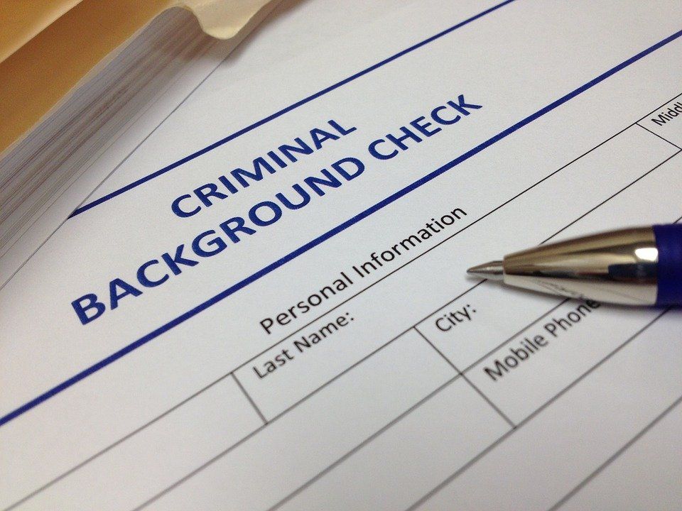A pen rests on top of a criminal background check form