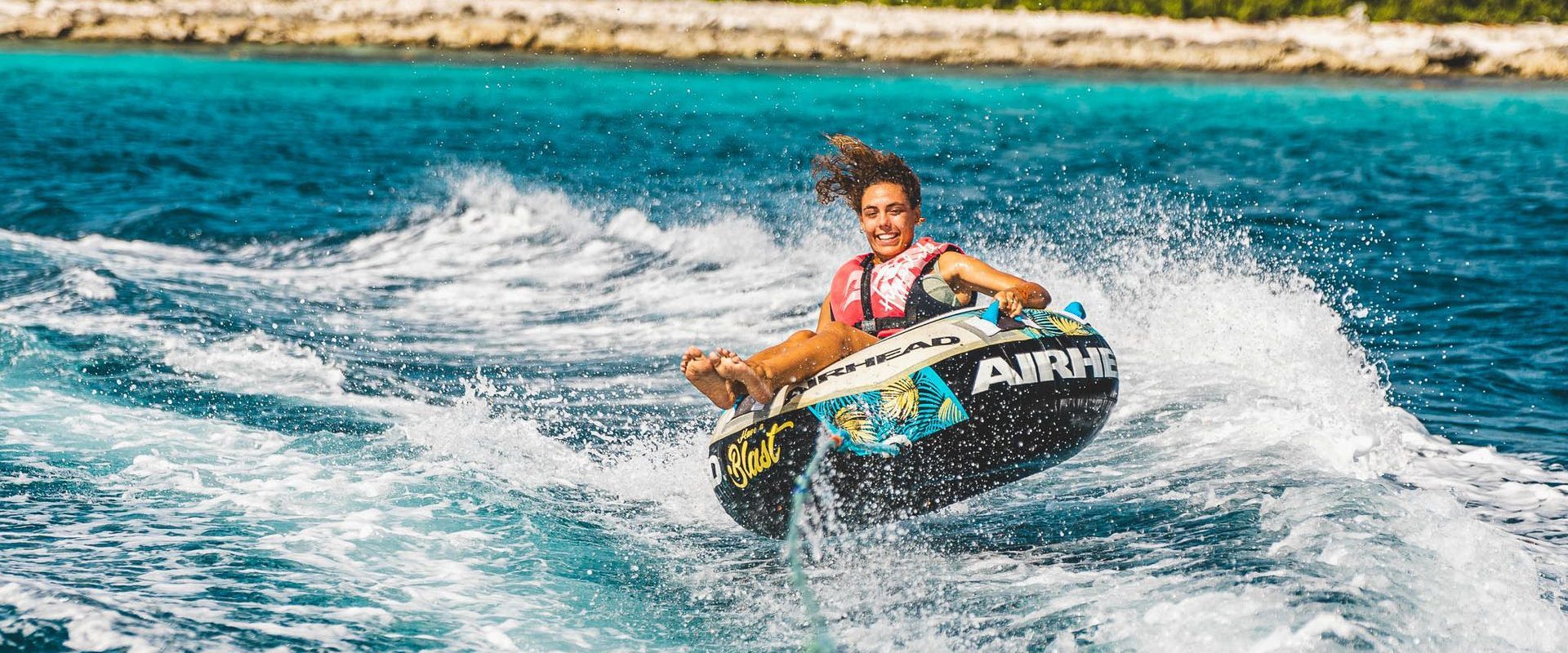 young woman is tubing behind motor boat rental from Blue Bay Bonaire on Caribbean Sea. 