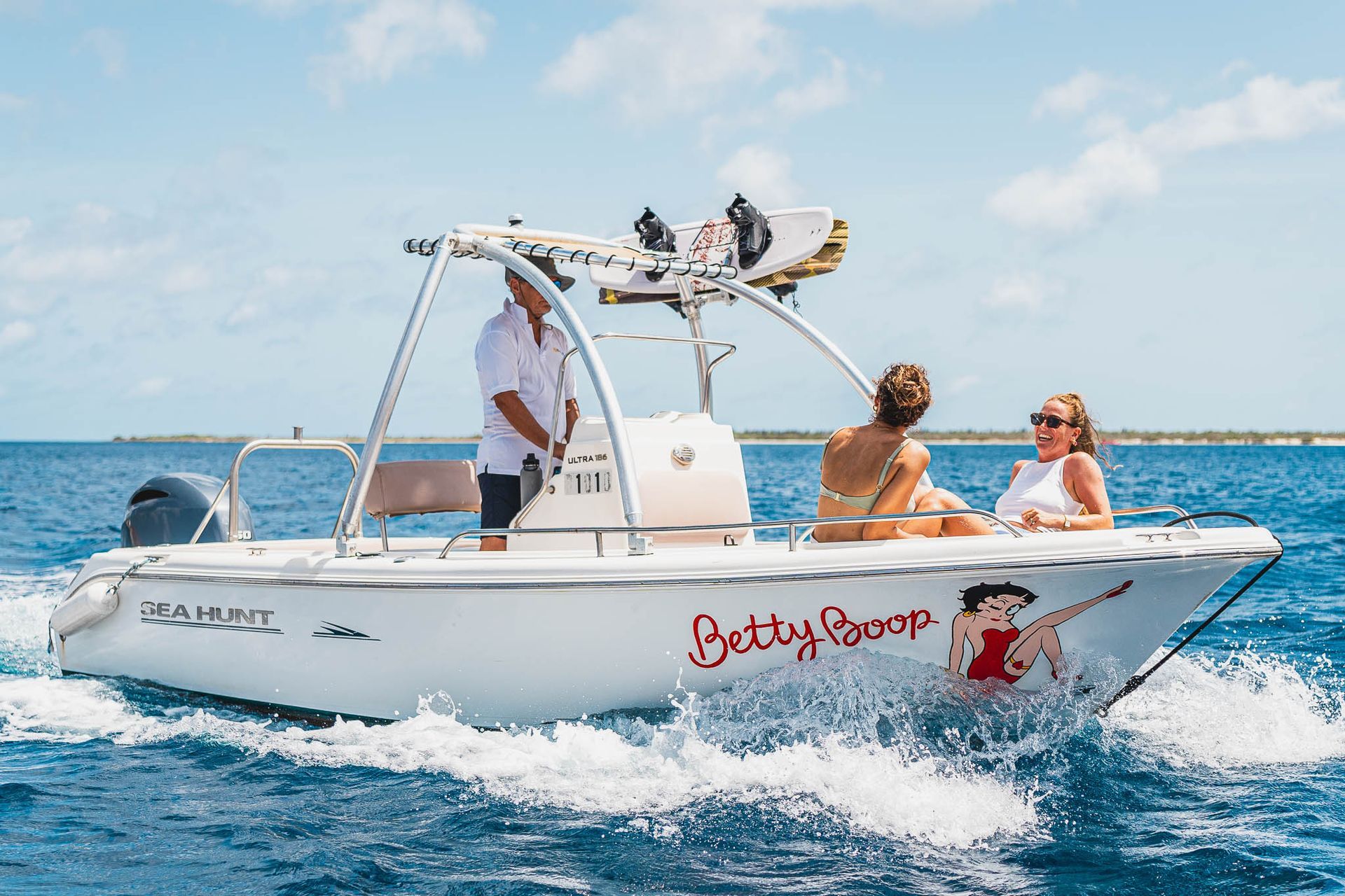 Blue Bay Bonaire Boat Rental Betty Boop Motorboat cruising on light blue caribbean sea.