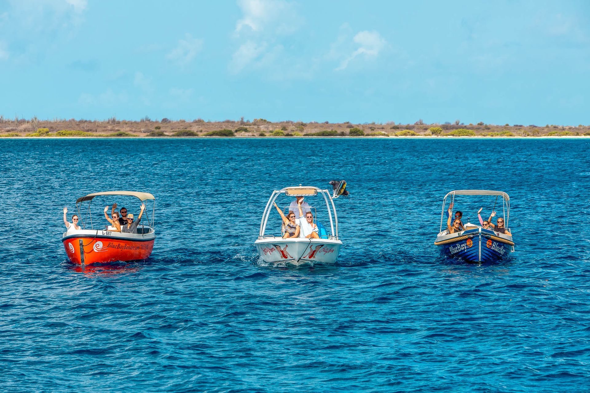 Three Motorboats Rental Bonaire Blue Bay with people cruising next to eachother towards camera.