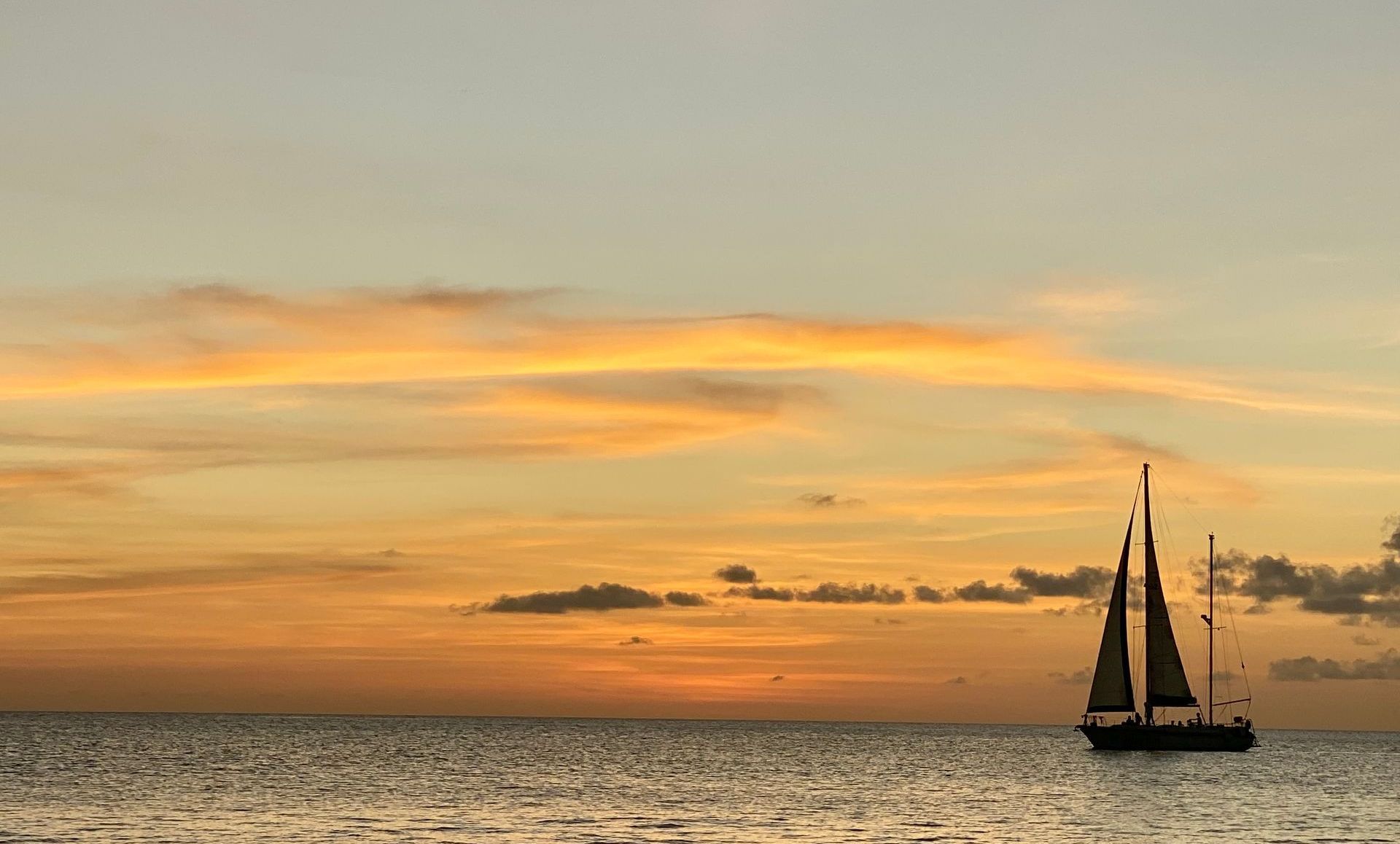 Blue Bay Bonaire Sunset Sail Tour, silhouet of sailboat in front of setting sun on Caribbean Sea.