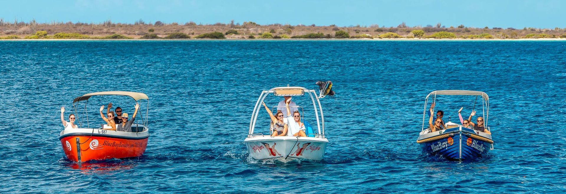 Drie motorboten van Blue Bay Bonaire liggen naast elkaar in het water voor Klein Bonaire