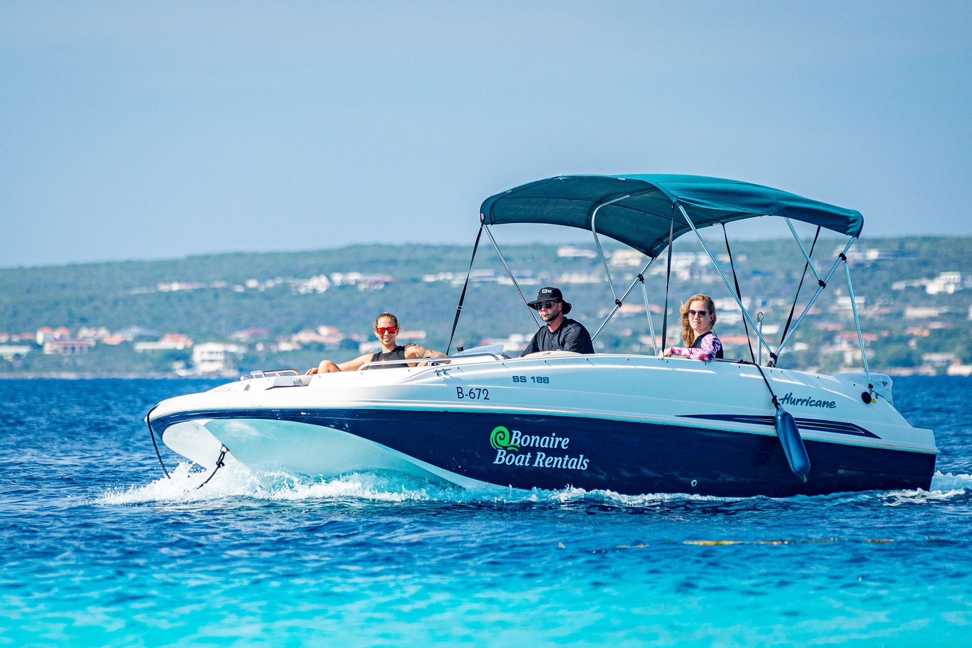 Blue Motor Boat Rental lying in light blue Caribbean Sea, three young women swimming and snorkling.