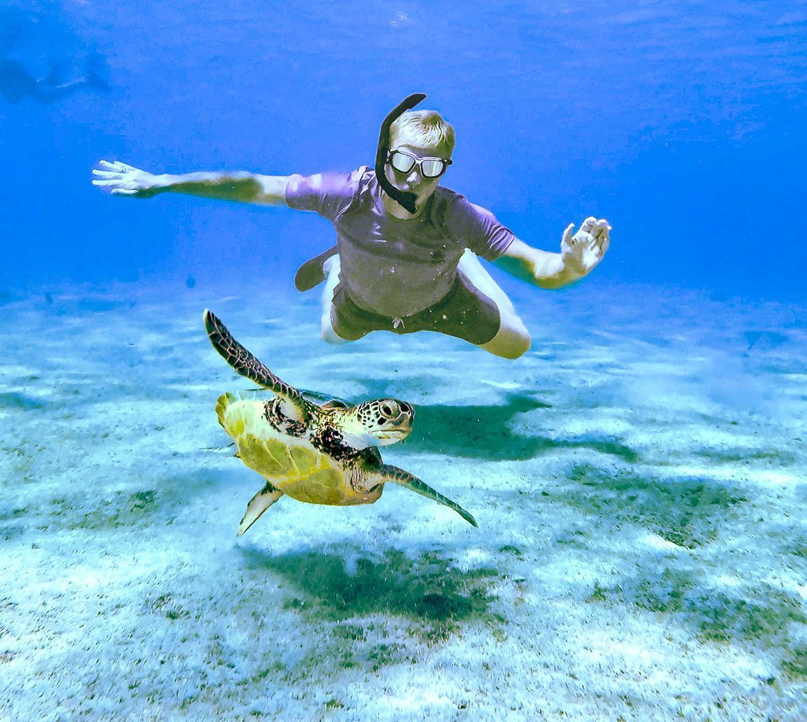 Blue Bay Bonaire Boat Rental Yellow sloep with 2 kids in the front making a heart to the camera