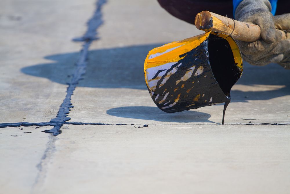 A person is pouring liquid from a bucket onto a concrete surface.