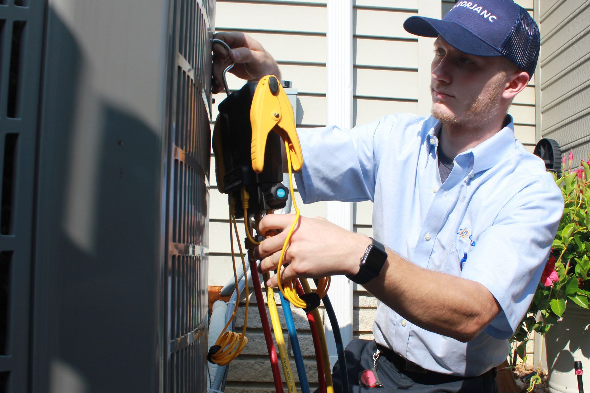 A man is working on an air conditioner outside of a house.