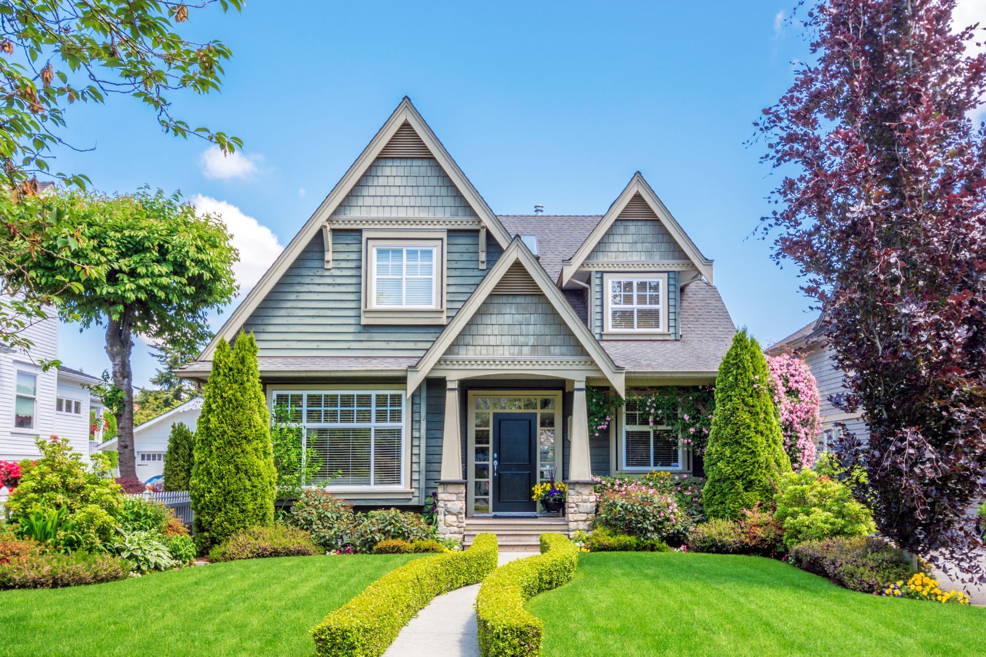 A large Cleveland house with a lush green lawn and trees in the summer sun.