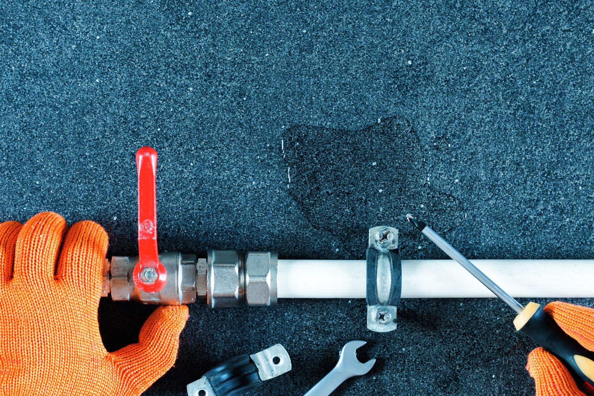 A Person is Fixing a Pipe With a Wrench and a Screwdriver