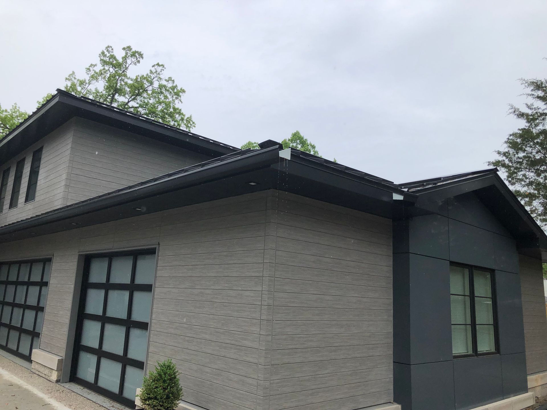 A house with a garage door and a black roof.