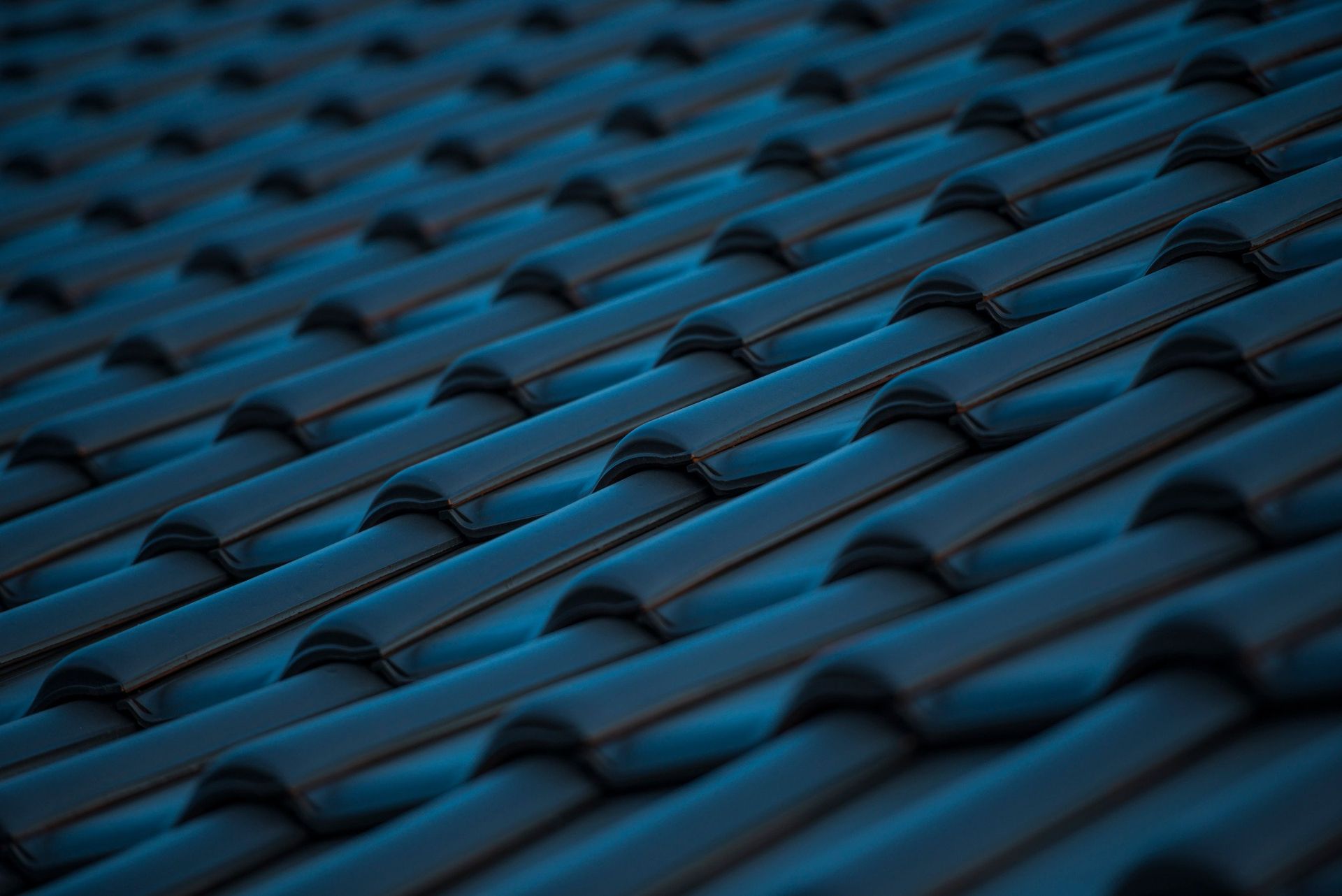 A close up of a row of blue tiles on a roof.