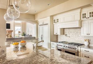 Elegant kitchen with granite countertops, white cabinets, and large island with pendant lights.