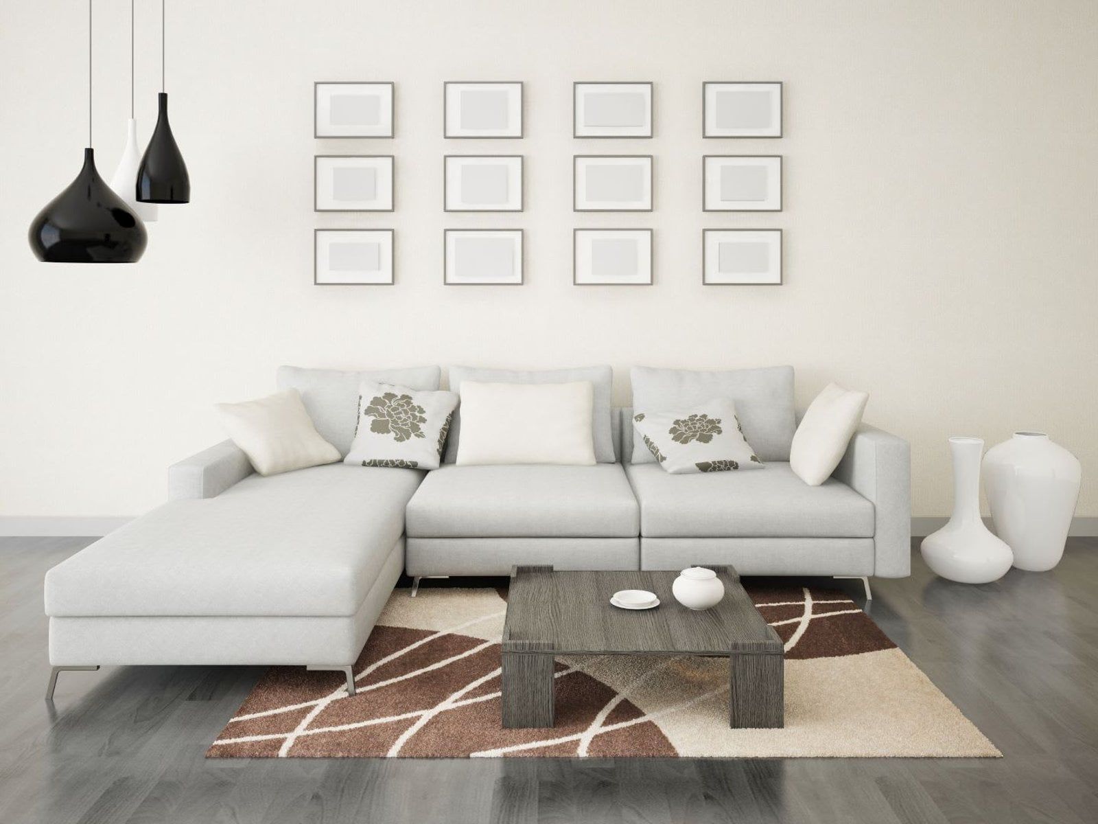 Modern living room with light gray sectional sofa, coffee table, and rug. Black pendant lights and framed photos on the wall.