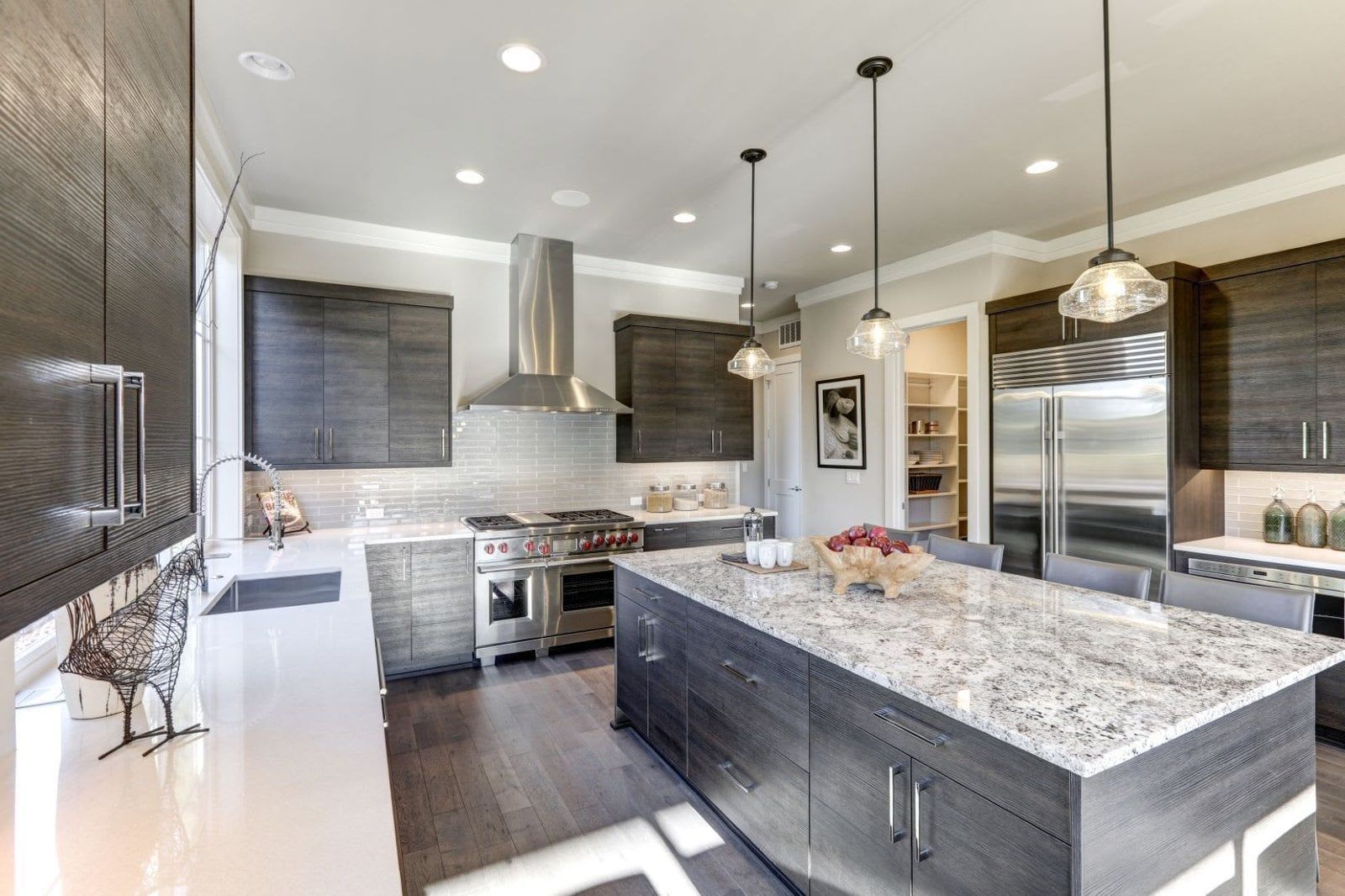 Modern kitchen with dark wood cabinets, stainless steel appliances, and large island with granite countertop.