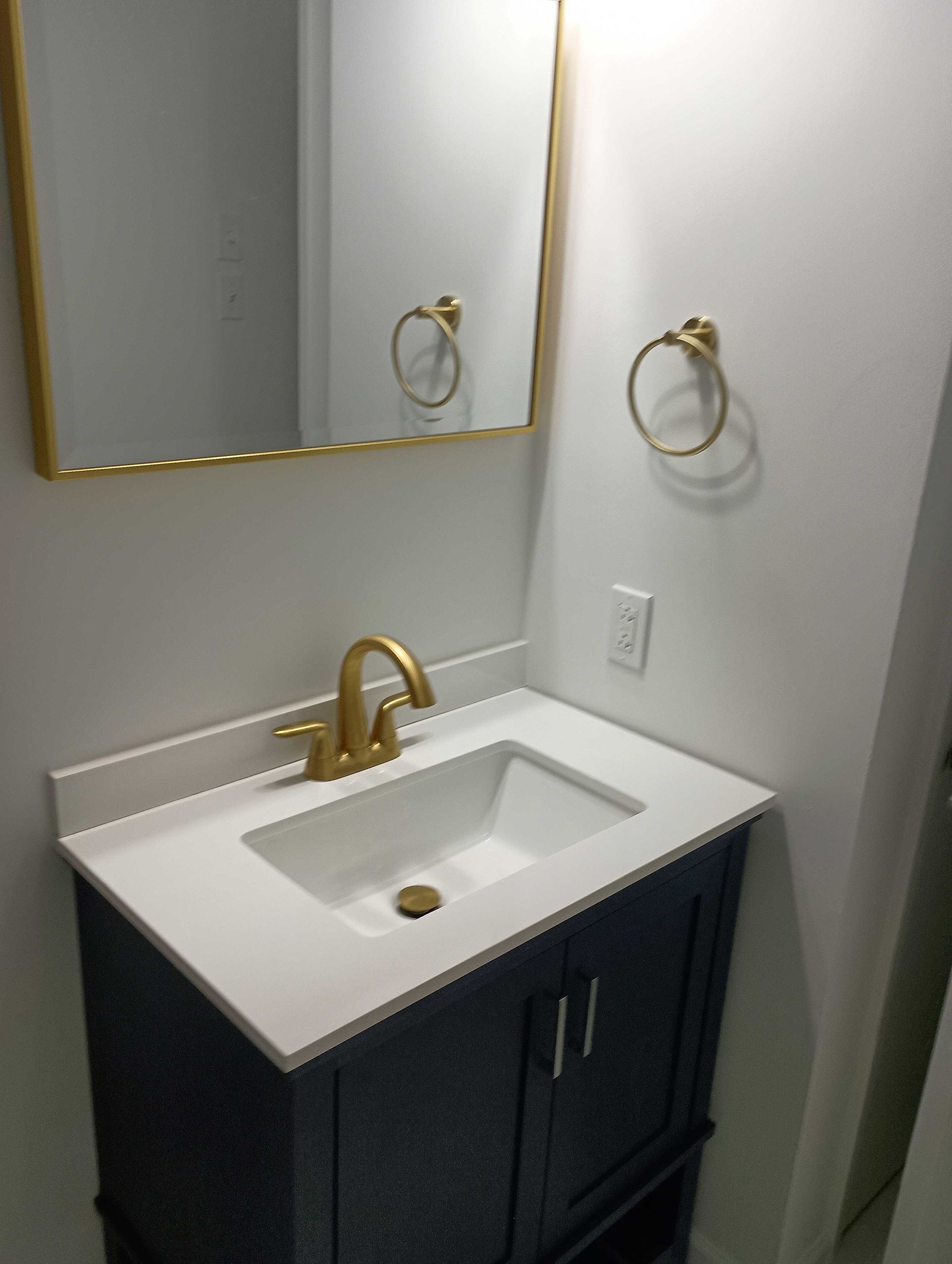 A Bathroom Sink With A Gold Faucet And A Mirror — Knoxville, TN — DABZ CO LLC Electrical & Building Contractors