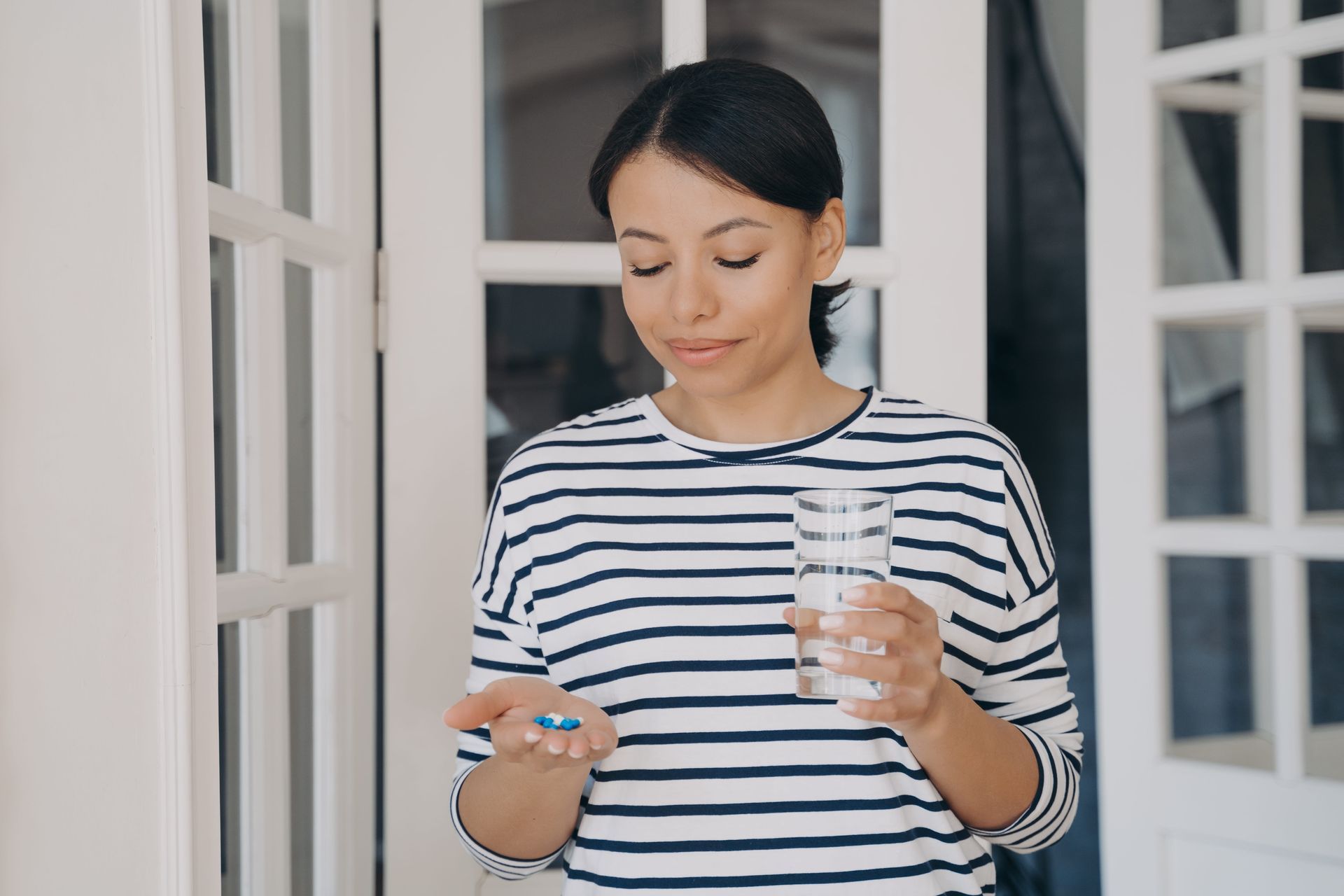 Young person wearing headphones, looking at a smartphone, studying in a library.