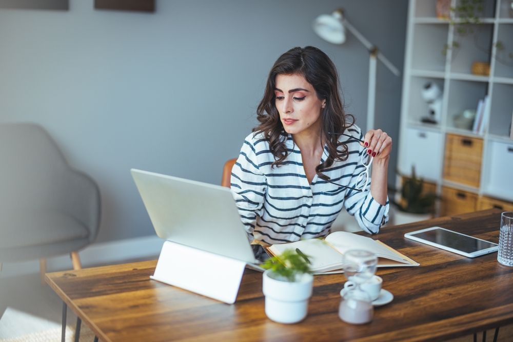 A woman is sitting at a table using a laptop computer.