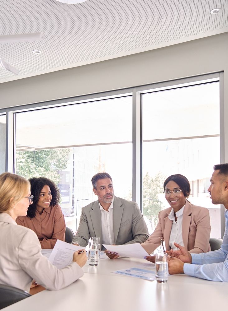 A group of m&a advisors are sitting at a table in an office having a meeting.