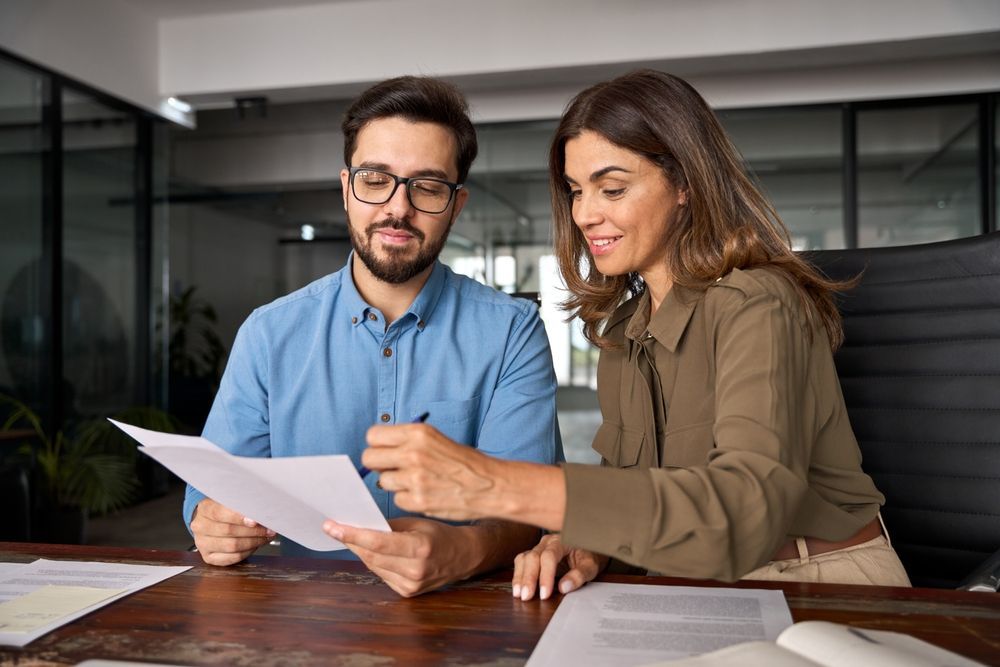 A man and a woman are sitting at a table looking at a piece of paper.