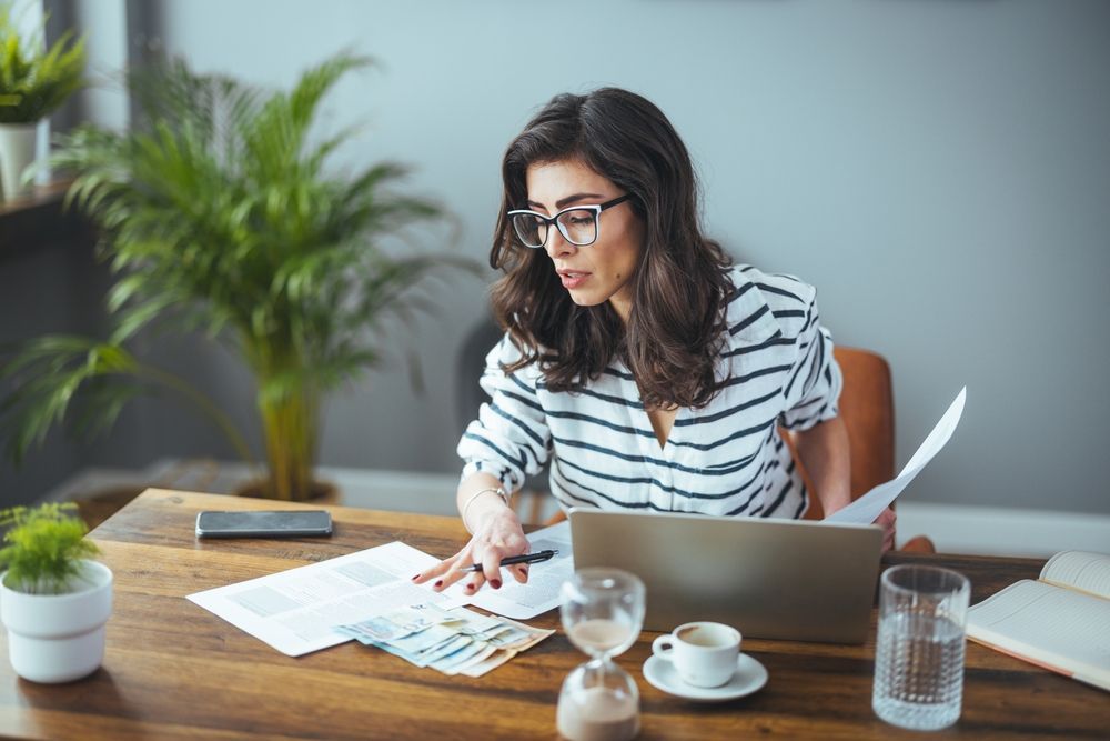 A woman is sitting at a desk using a laptop computer.