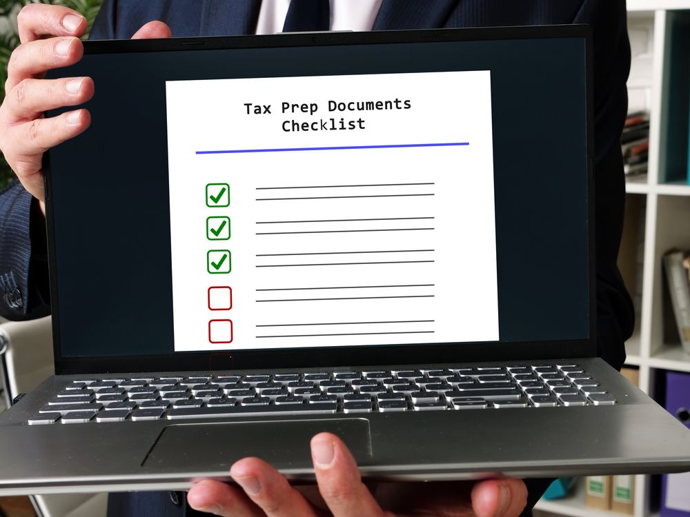 a man holding a laptop with a small business tax preparation checklist on it