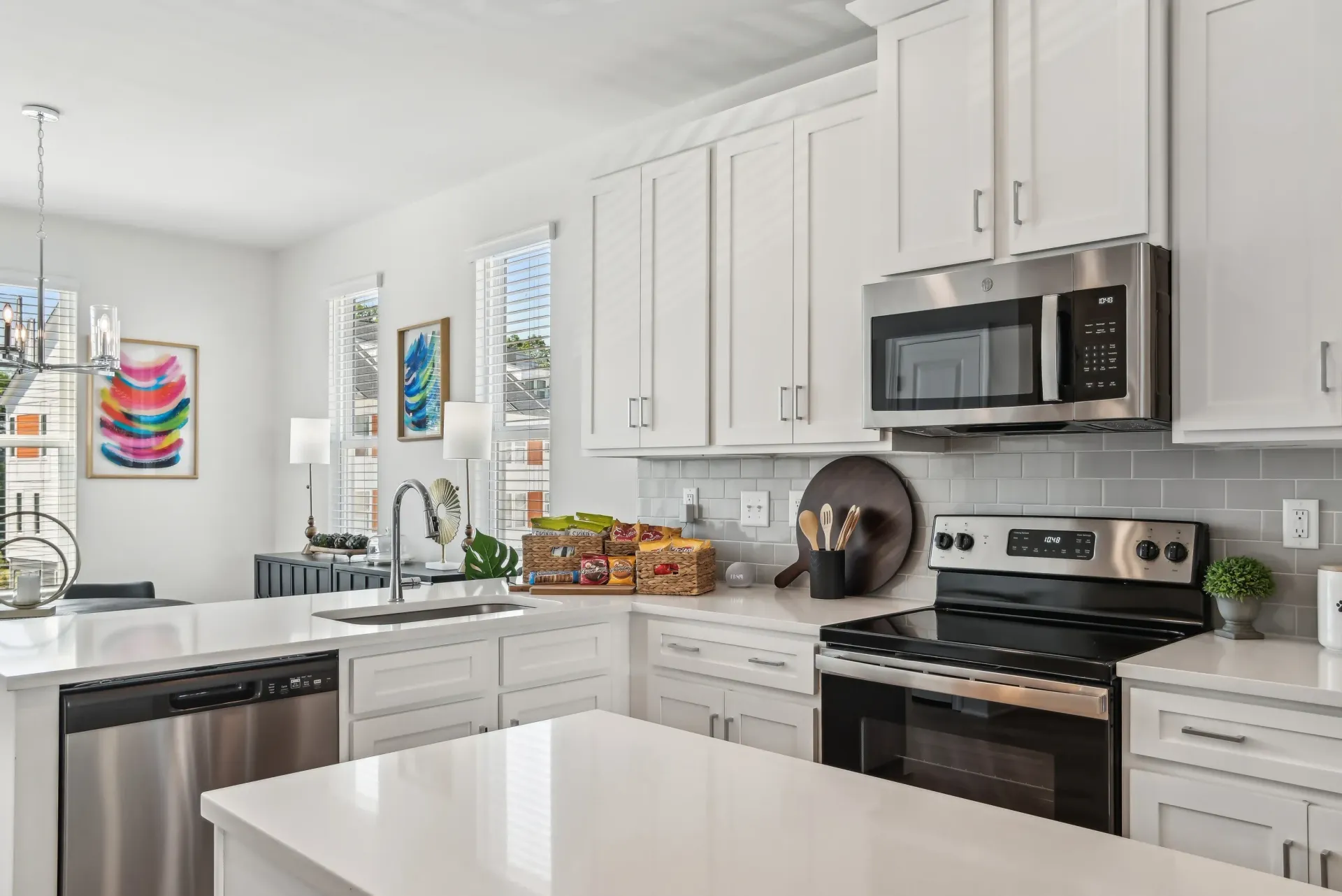Bright white kitchen in an apartment with stainless steel appliances and an island.
