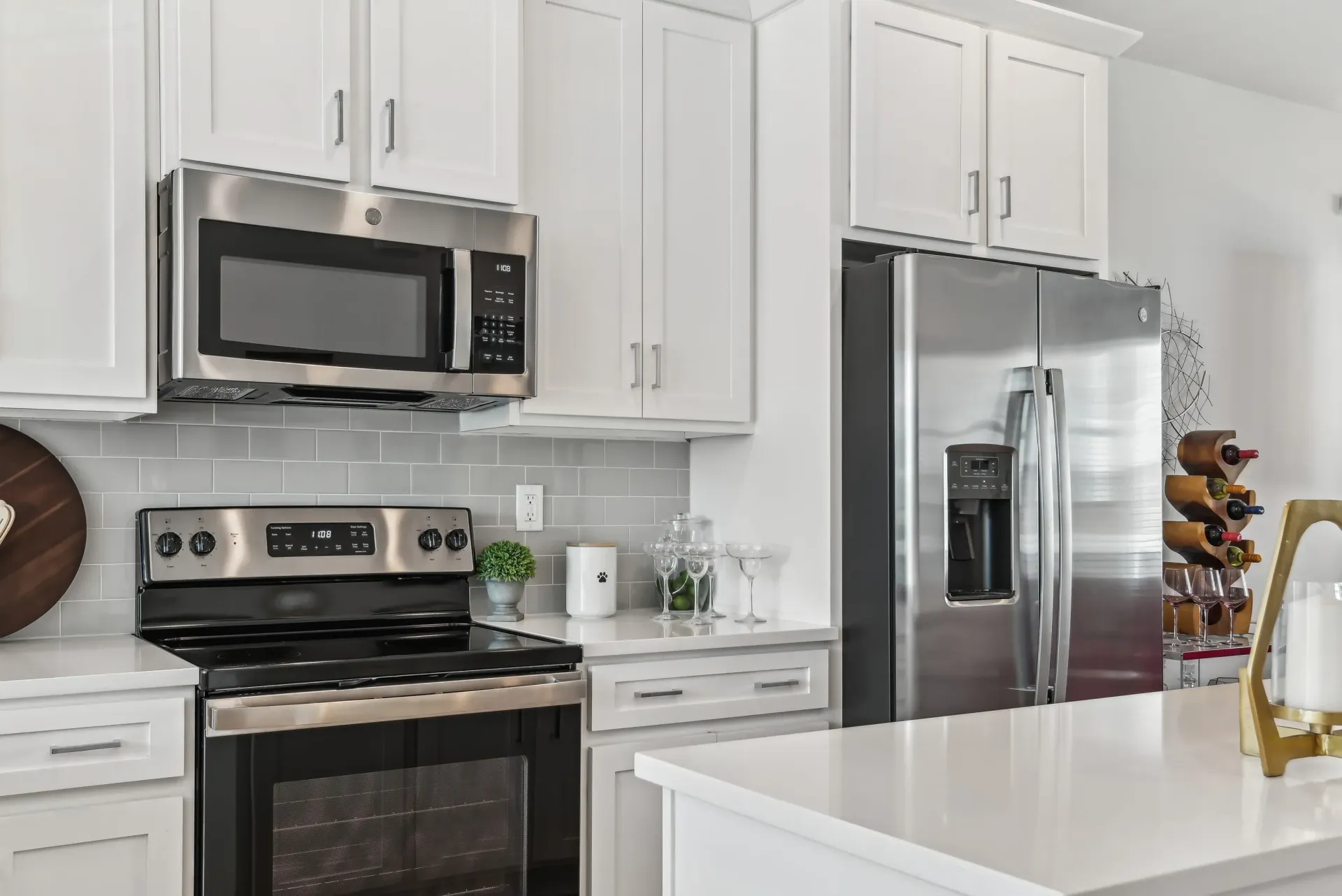 Modern white kitchen with stainless steel fridge, microwave, and stove.