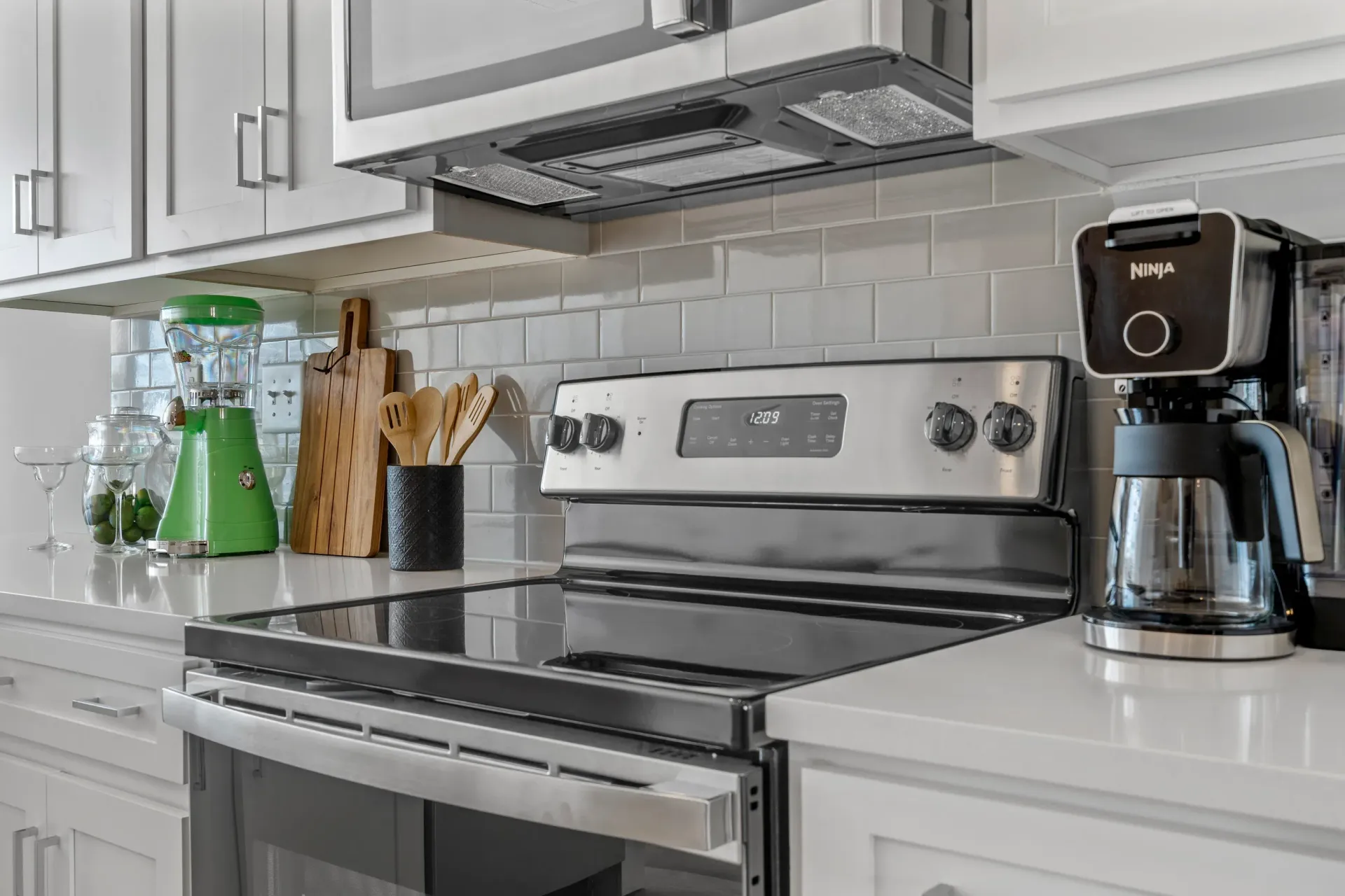 Kitchen with stainless steel appliances: range, microwave, and coffee maker. White cabinets and countertops.