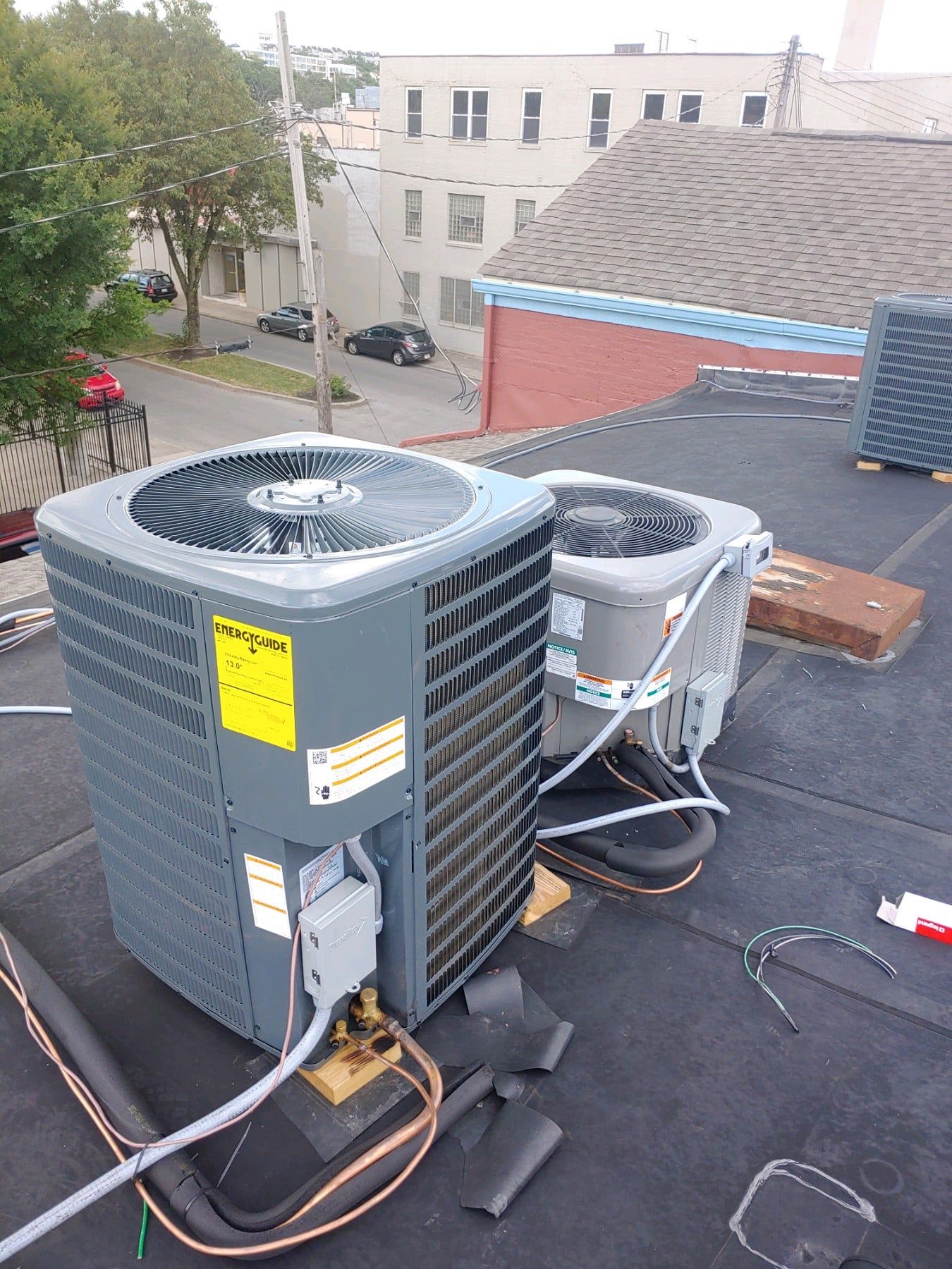 Two air conditioners are sitting on top of a roof.
