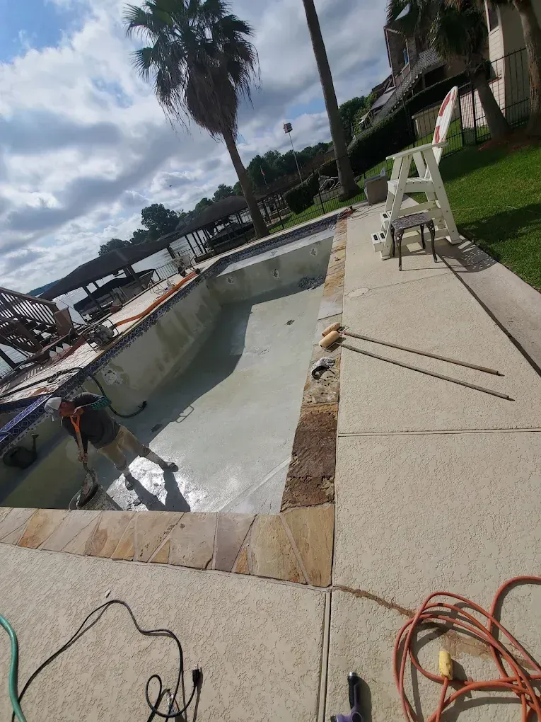 A man is working on the side of a swimming pool.