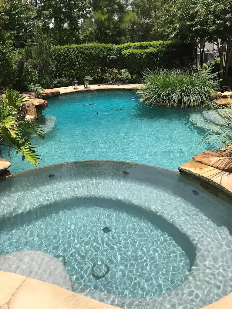 A large swimming pool with a hot tub in the middle of it.