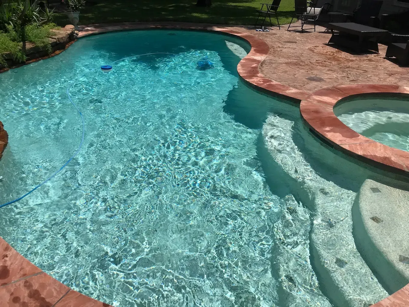 A large swimming pool with stairs and a hot tub