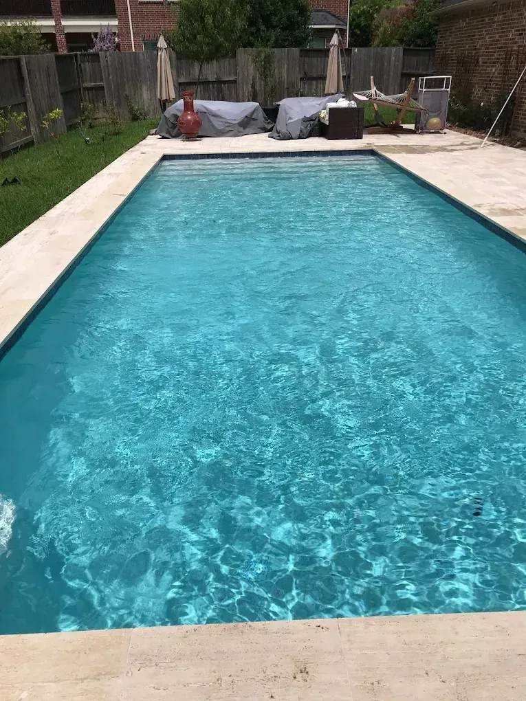 A large swimming pool filled with blue water in a backyard.