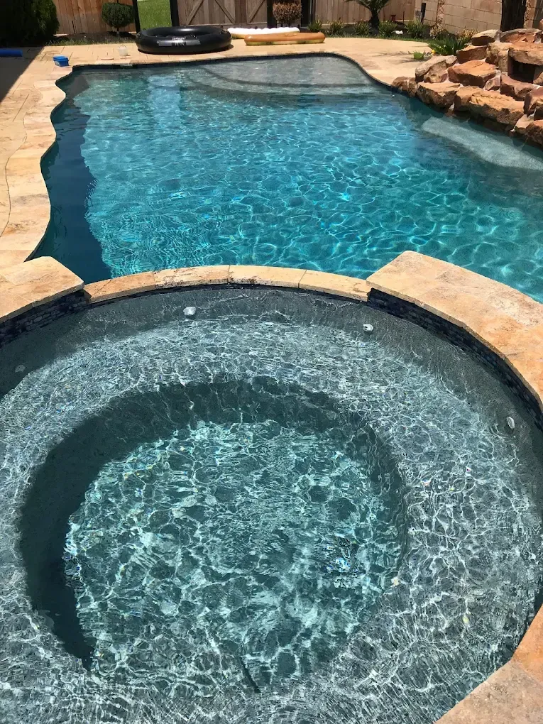 A large swimming pool with a hot tub in the middle of it.