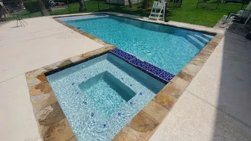 A large swimming pool with a hot tub in the middle of it.