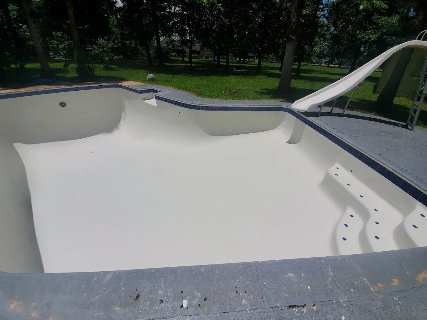 A white swimming pool with a slide in the backyard