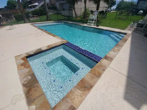 A large swimming pool with a hot tub in the middle of it.