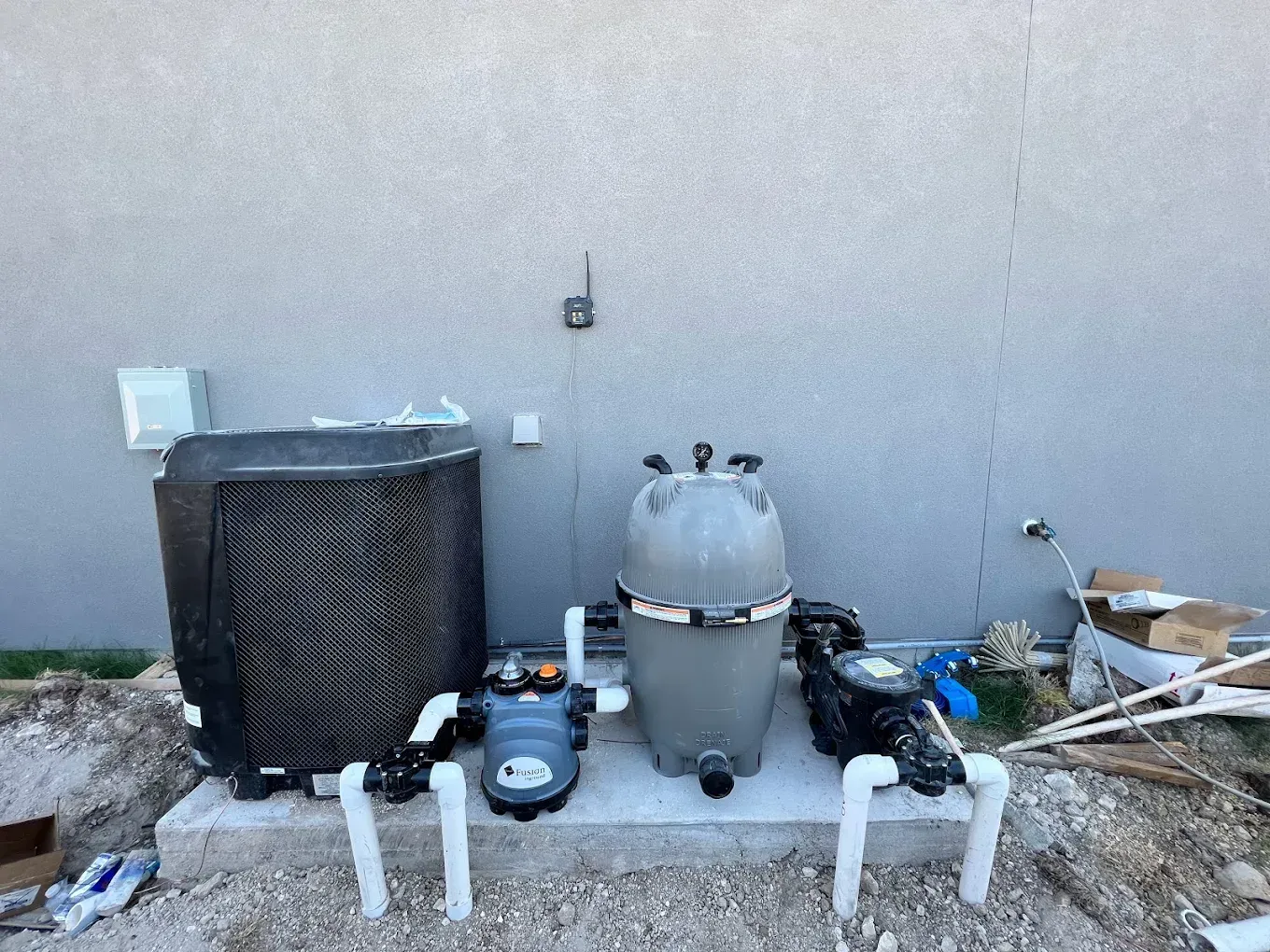A swimming pool filter is sitting on top of a concrete platform next to a wall.