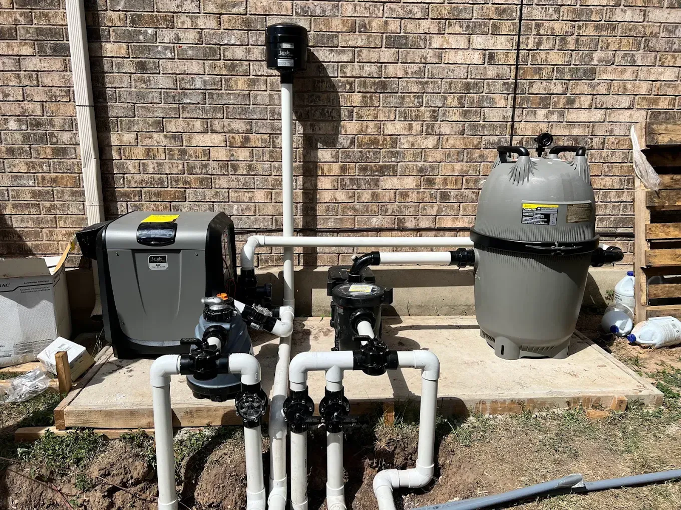 A swimming pool system is being installed in front of a brick building.