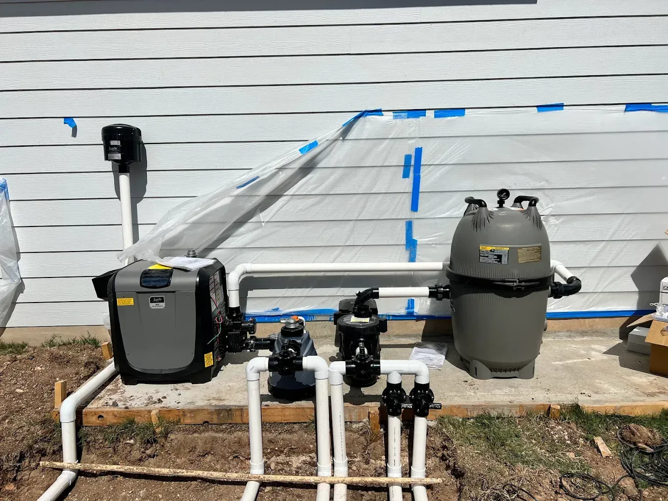 A swimming pool system is being installed on the side of a house.