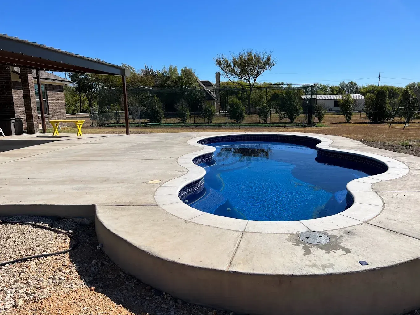 A large swimming pool is surrounded by a concrete deck