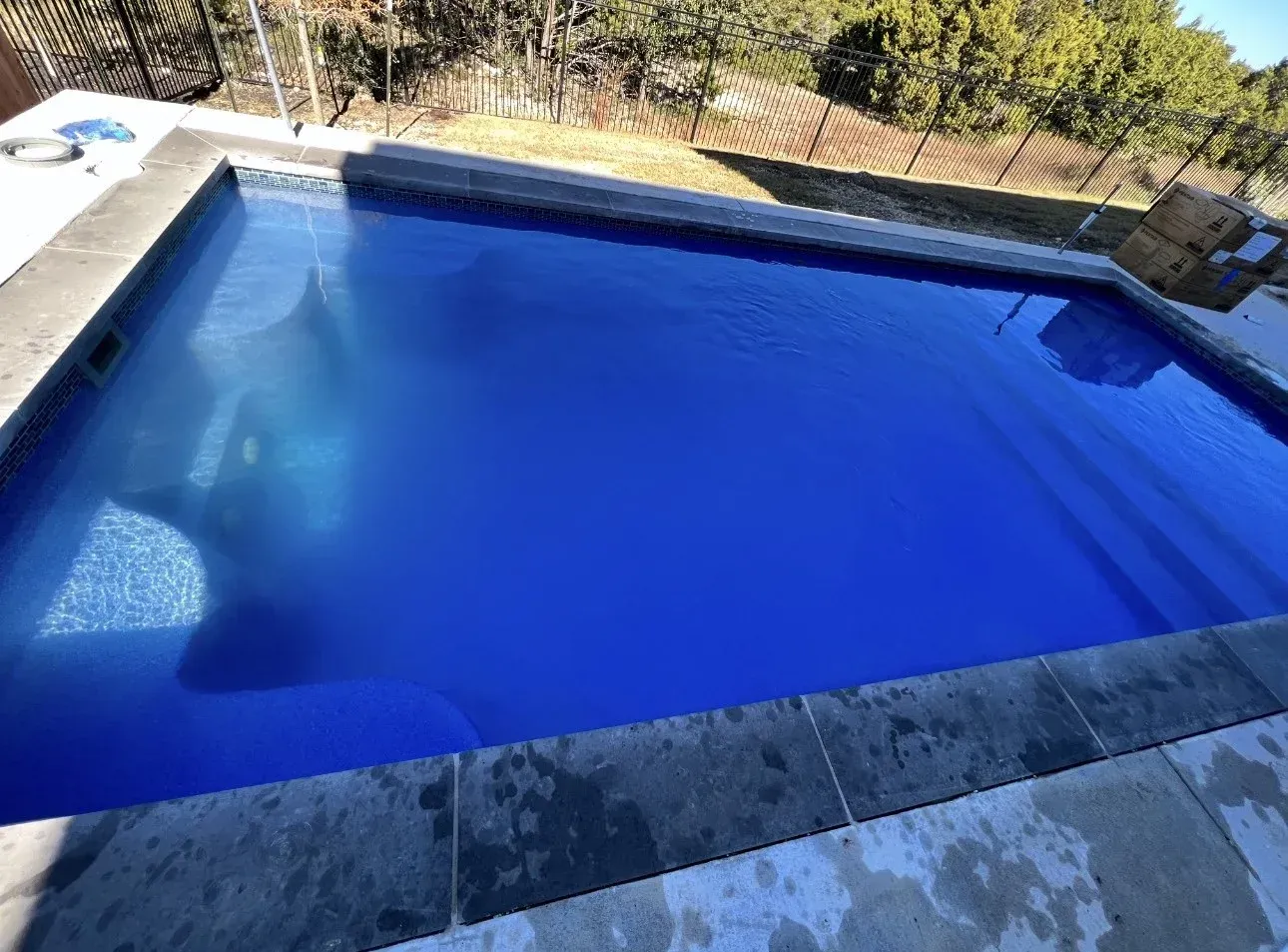 A large blue swimming pool with a fence in the background