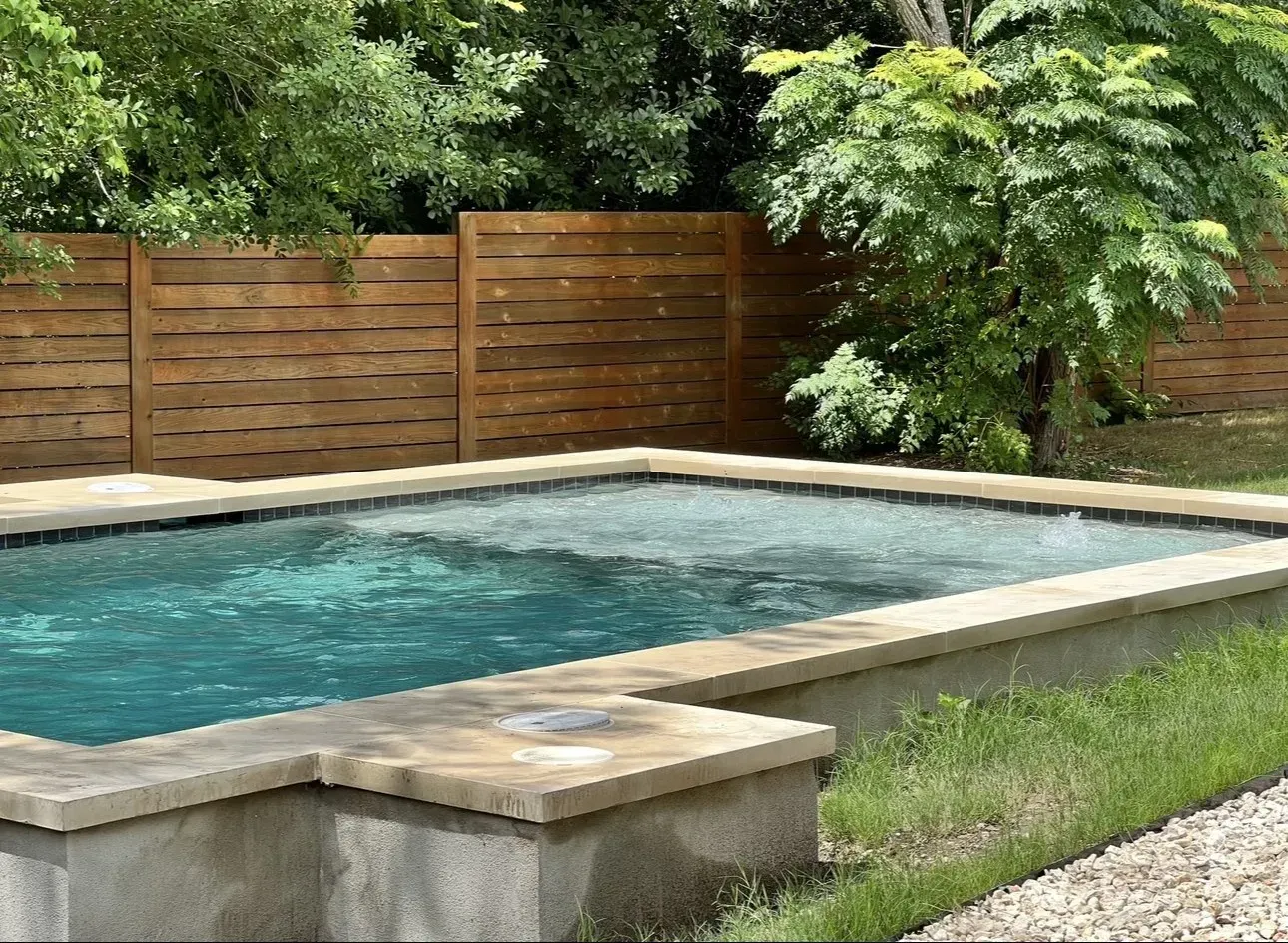 A large swimming pool with a wooden fence surrounding it.