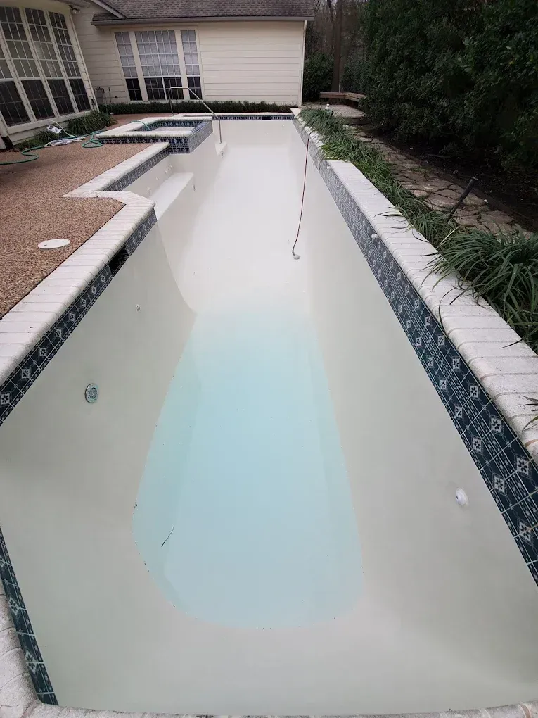 A very long swimming pool with a house in the background.